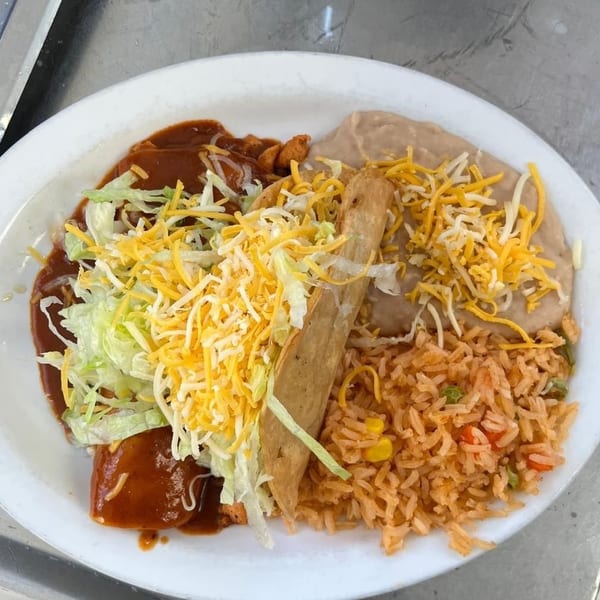 Mexican combo plate with a crispy taco, enchiladas, refried beans, rice, lettuce, shredded cheese, and red sauce.